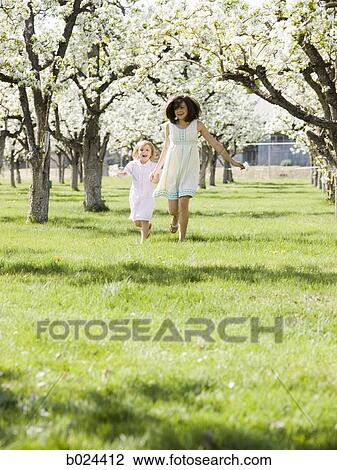 two girls in a blossoming orchard View Large Photo Image Stock Image - two girls in a blossoming orchard. Fotosearch