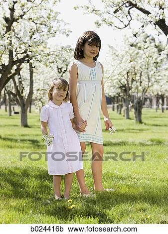 Stock Image - two girls in a blossoming orchard. Fotosearch