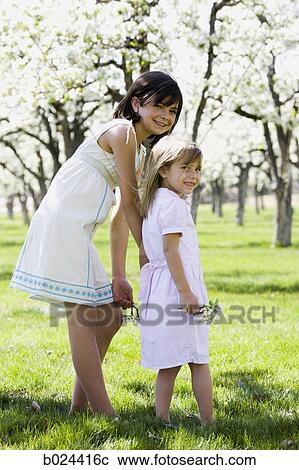 Stock Image - two girls in a blossoming orchard. Fotosearch