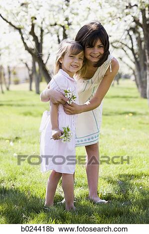 Stock Image - two girls in a blossoming orchard. Fotosearch