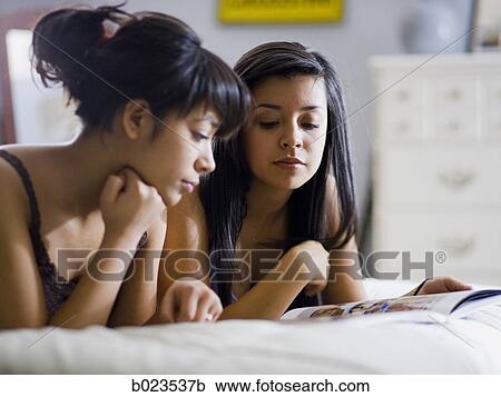 two girls lying on a bed View Large Photo Image Stock Image - two girls lying on a bed. Fotosearch