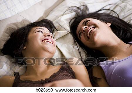 two girls lying on a bed View Large Photo Image Stock Image - two girls lying on a bed. Fotosearch