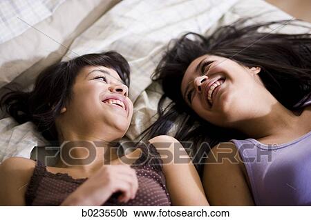 two girls lying on a bed View Large Photo Image Stock Image - two girls lying on a bed. Fotosearch