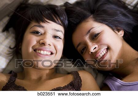 Stock Image - two girls lying on a bed. Fotosearch