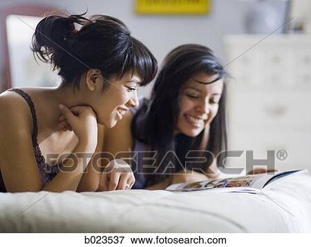 two girls lying on a bed View Large Photo Image Stock Photo - two girls lying on a bed. Fotosearch