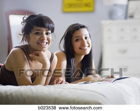two girls lying on a bed View Large Photo Image Stock Photo - two girls lying on a bed. Fotosearch