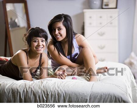 two girls lying on a bed View Large Photo Image Stock Photograph - two girls lying on a bed. Fotosearch