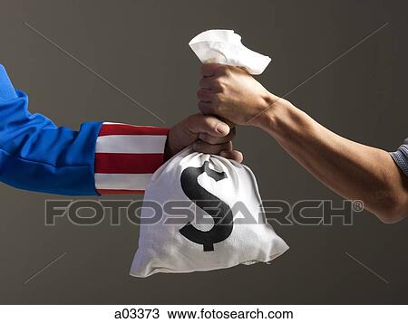 Stock Image - Two men holding bag with money, studio shot. Fotosearch