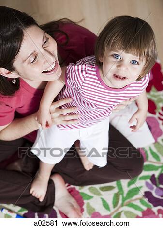 Stock Image - USA, California, San Francisco, mother with daughter (2-3) standing on her laps. Fotosearch