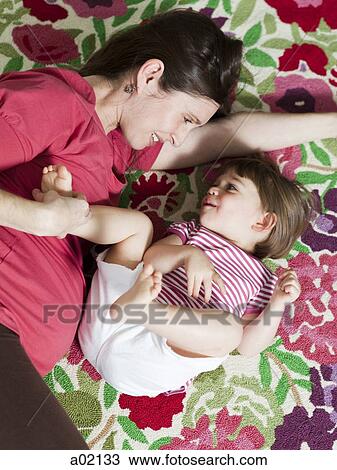 Stock Image - USA, California, San Francisco, pregnant mother with daughter (2-3) on bed. Fotosearch