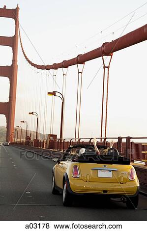 Stock Photo - USA, California, San Francisco, yellow car on Golden Gate Bridge. Fotosearch