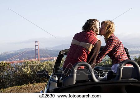 USA, California, San Francisco, young couple sitting in convertible car and kissing, Golden Gate Bridge in background View Large Photo Image Stock Image - USA, California, San Francisco, young couple sitting in convertible car and kissing, Golden Gate Bridge in background. Fotosearch