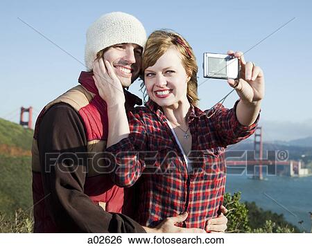 USA, California, San Francisco, young couple taking pictures of themselves, Golden Gate Bridge in background View Large Photo Image Stock Photograph - USA, California, San Francisco, young couple taking pictures of themselves, Golden Gate Bridge in background. Fotosearch