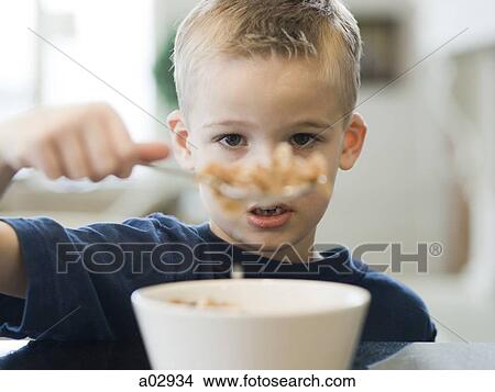 Picture - USA, Utah, Alpine, boy (6-7) eating cereals by table, portrait. Fotosearch
