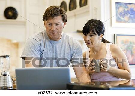Stock Image - USA, Utah, Alpine, couple standing and looking at laptop. Fotosearch