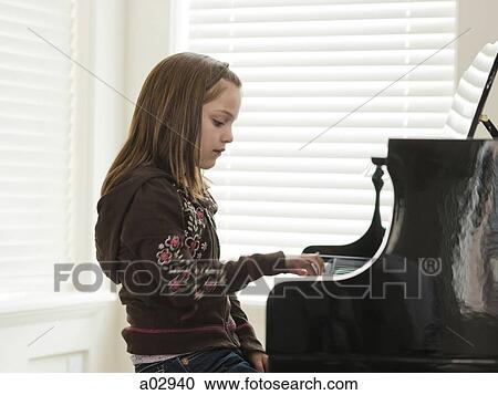 Stock Image - USA, Utah, Alpine, girl (8-9) practicing piano, side view. Fotosearch