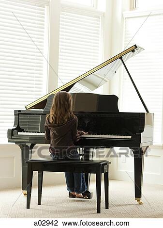 Stock Image - USA, Utah, Alpine, girl (8-9) practicing piano, rear view. Fotosearch