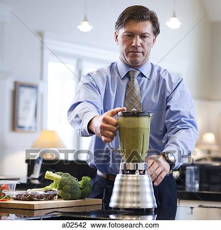 Stock Image - USA, Utah, Alpine, mature man preparing vegetable drink. Fotosearch