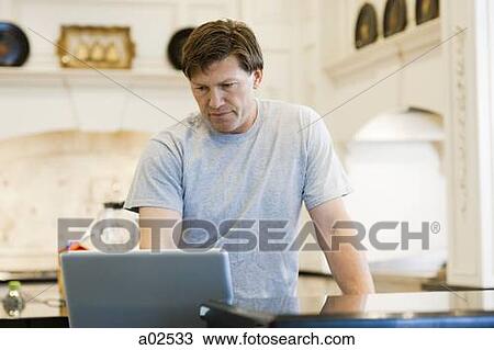Stock Image - USA, Utah, Alpine, mature man standing and looking at laptop. Fotosearch