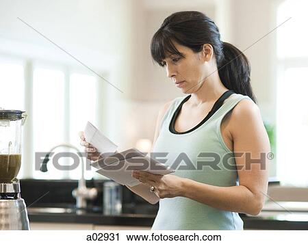 Stock Image - USA, Utah, Alpine, mid adult woman holding letters in kitchen. Fotosearch