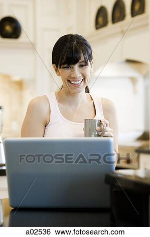 USA, Utah, Alpine, mid adult woman sitting behind laptop and smiling View Large Photo Image Stock Photograph - USA, Utah, Alpine, mid adult woman sitting behind laptop and smiling. Fotosearch