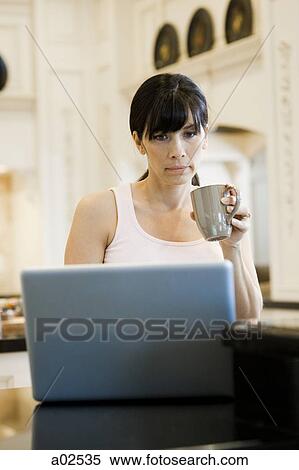 USA, Utah, Alpine, mid adult woman sitting behind laptop and holding mug View Large Photo Image Stock Photography - USA, Utah, Alpine, mid adult woman sitting behind laptop and holding mug. Fotosearch