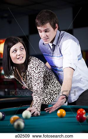 Stock Photo - USA, Utah, American Fork, young couple playing pool. Fotosearch