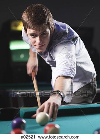 Stock Image - USA, Utah, American Fork, young man playing pool. Fotosearch