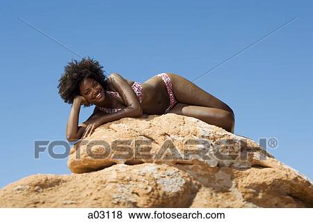 Stock Photo - USA, Utah, Lake Powell, young woman in bikini lying on rocks. Fotosearch