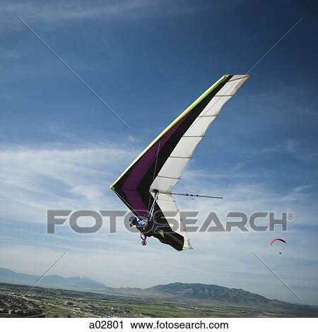 Stock Image - USA, Utah, Lehi, mid adult man hang gliding, low angle view. Fotosearch