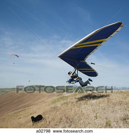 Stock Photo - USA, Utah, Lehi, young man taking off with hang glider. Fotosearch