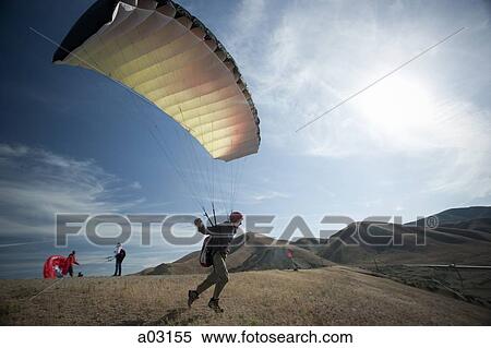 Stock Photography - USA, Utah, Lehi, young paraglider starting from hill. Fotosearch