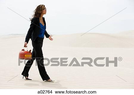 USA, Utah, Little Sahara, young businesswoman walking on desert carrying gas can View Large Photo Image Picture - USA, Utah, Little Sahara, young businesswoman walking on desert carrying gas can. Fotosearch