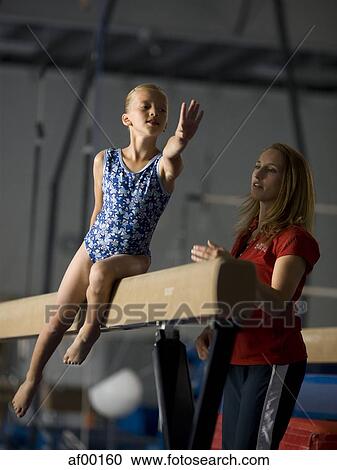 Stock Image - USA, Utah, Orem, girl (10-11) exercising on balance beam with teacher. Fotosearch