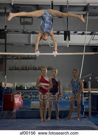 Stock Photograph - USA, Utah, Orem, girls (10-11) in gym watching friend exercising on pole. Fotosearch