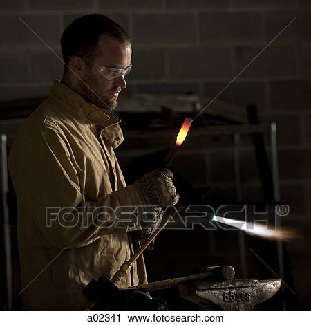 Stock Image - USA, Utah, Orem, male welder with blowtorch in workshop. Fotosearch