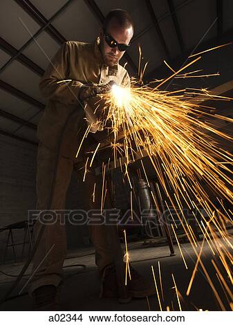 Picture - USA, Utah, Orem, man welding metal in workshop. Fotosearch