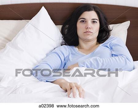 Stock Photo - USA, Utah, Orem, portrait of young woman lying in bed. Fotosearch