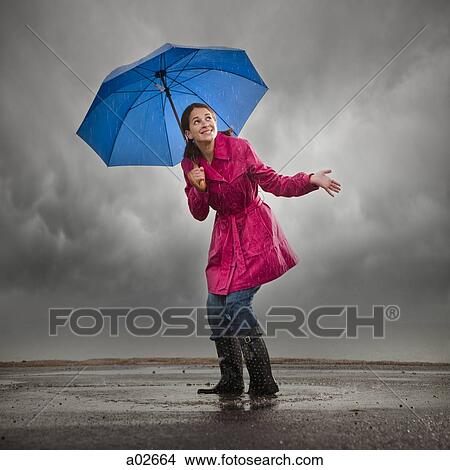 Picture - USA, Utah, Orem, woman with umbrella standing in puddle. Fotosearch