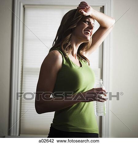 Stock Image - USA, Utah, Orem, young woman standing with bottle of water. Fotosearch
