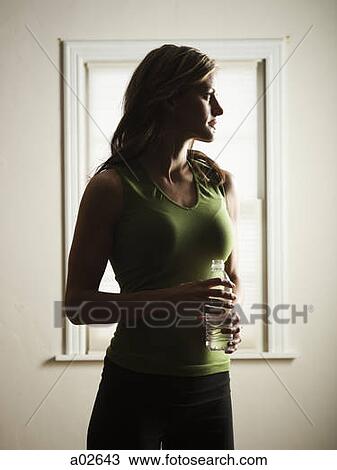 Stock Image - USA, Utah. Orem, young woman standing and holding water bottle. Fotosearch