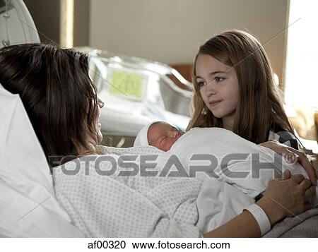 Stock Image - USA, Utah, Payson, Girl (8-9) with mother and baby boy (0-1 months) in bed. Fotosearch
