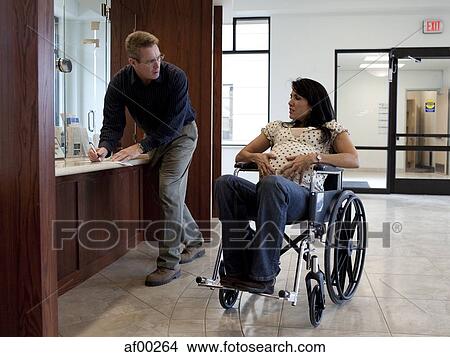 Picture - USA, Utah, Payson, Pregnant woman waiting when man filling some medical documents. Fotosearch