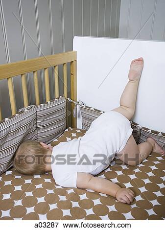 Stock Photo - USA, Utah, Provo, Baby boy (18-23 months) lying in crib. Fotosearch