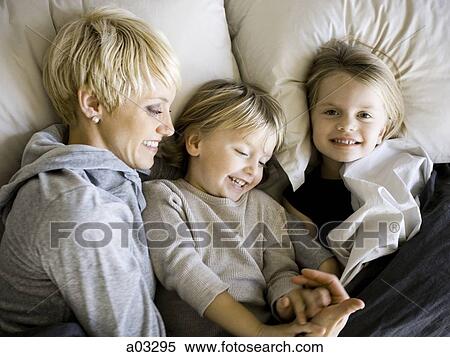 Stock Photography - USA, Utah, Provo, Boy and girl (2-5) in bed with mother. Fotosearch