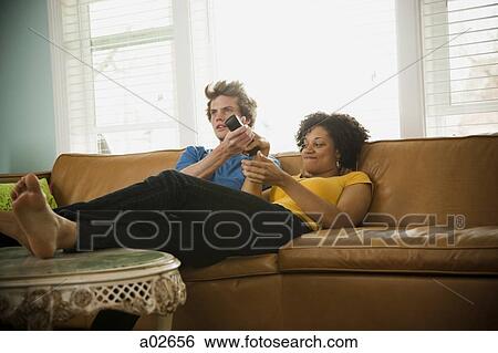 USA, Utah, Provo, couple sitting on sofa watching TV View Large Photo Image Stock Photograph - USA, Utah, Provo, couple sitting on sofa watching TV. Fotosearch