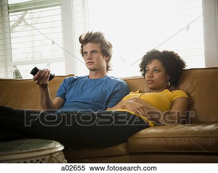 USA, Utah, Provo, couple sitting on sofa watching TV View Large Photo Image Stock Photography - USA, Utah, Provo, couple sitting on sofa watching TV. Fotosearch