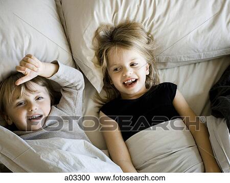 Stock Image - USA, Utah, Provo, Portrait of brother and sister (2-5) lying in bed. Fotosearch