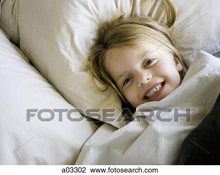 Stock Image - USA, Utah, Provo, Portrait of girl (4-5) lying in bed. Fotosearch