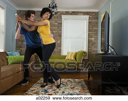 USA, Utah, Provo, young couple holding remote control in living room View Large Photo Image Stock Photo - USA, Utah, Provo, young couple holding remote control in living room. Fotosearch